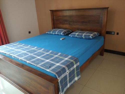 a bed with a wooden headboard and two pillows at Negombo New Villa in Negombo