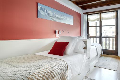 a bedroom with a white bed with a red wall at Val de Ruda Luxe 21 by FeelFree Rentals in Baqueira-Beret