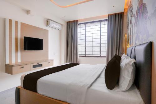 a bedroom with a large bed with a tv on the wall at Super Townhouse Oak Dharwad New Bus Terminal Formerly Hotel Aditya Inn in Dhārwād