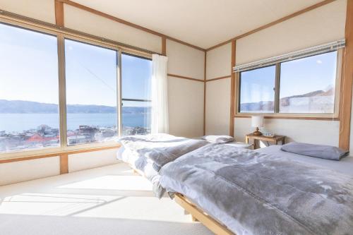 a bedroom with two beds and large windows at 諏訪絶景ハウス - Suwa Panorama House in Suwa