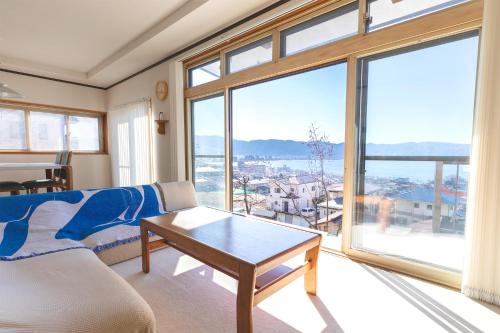 a living room with a table and a large window at 諏訪絶景ハウス - Suwa Panorama House in Suwa