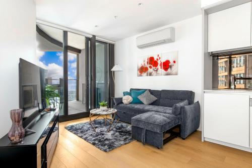 a living room with a couch and a tv at The Quarter Elite 1BR Resort-Style Amenities in Melbourne