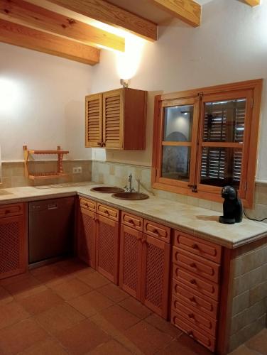 a kitchen with wooden cabinets and a sink and a window at Cozy Chalet with Sea Views & Private Pool in Valldemossa