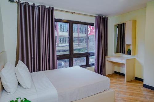 a bedroom with a bed and a large window at Olive Town Center and Hotel in Baguio