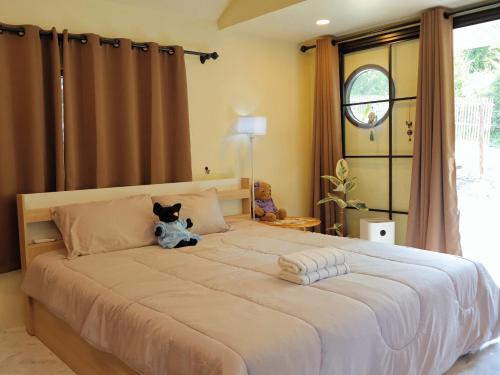 a bedroom with a large bed with a stuffed animal on it at chananthida suyarach in Ban Mai Na Hi