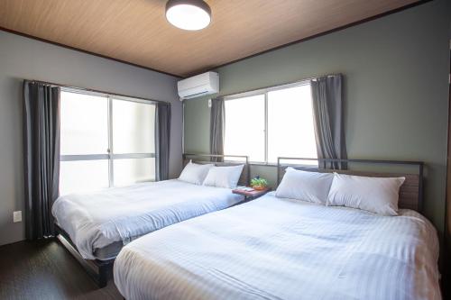 two beds in a room with two windows at H-1ビル 301 hiroshima in Hiroshima
