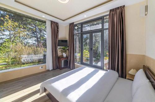 a bedroom with a bed and a large window at Hamilton Villa Da Lat - Pine Tree n Valley View in Khu Chi Lăng