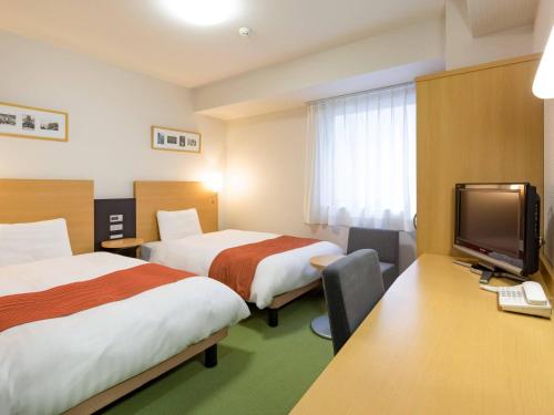 a hotel room with two beds and a flat screen tv at Comfort Hotel Yamagata in Yamagata