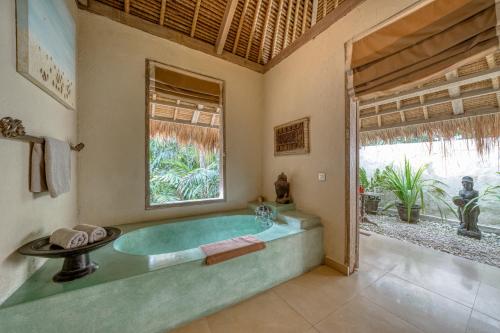 a bathroom with a large tub in a room with a window at Nomadic Resort Bali in Canggu