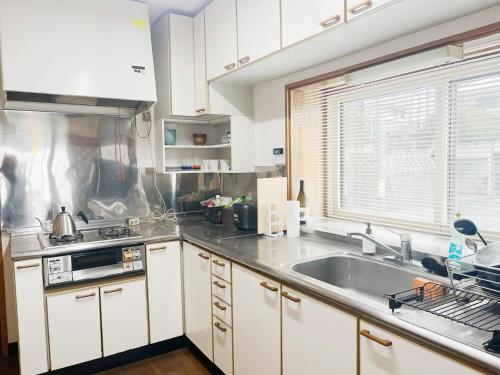 a kitchen with white cabinets and a stainless steel sink at 諏訪絶景ハウス - Suwa Panorama House in Suwa