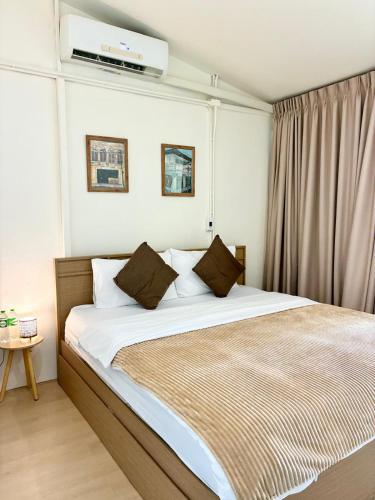 ein Schlafzimmer mit einem Bett mit weißen Laken und braunen Kissen in der Unterkunft Purr in Phuket