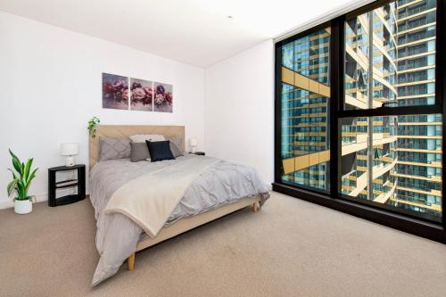a bedroom with a bed and a large window at The Quarter Elite 1BR Resort-Style Amenities in Melbourne
