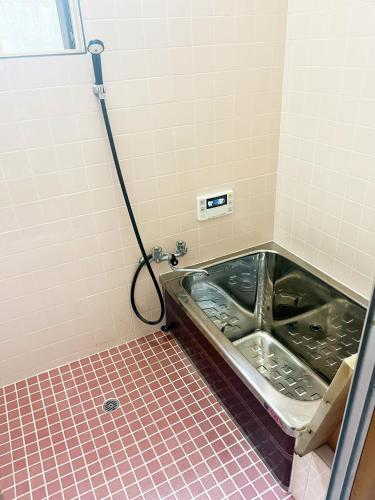 a bath tub in a bathroom with a tiled floor at 諏訪絶景ハウス - Suwa Panorama House in Suwa