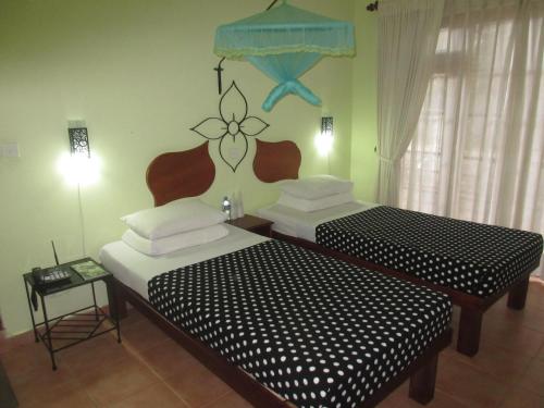 two twin beds in a room with at Nature Walk Resort in Kandy