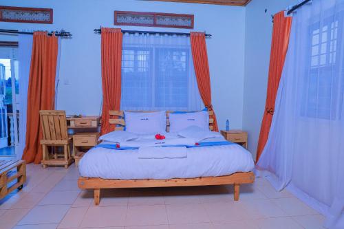 a bedroom with a large bed with orange curtains at Hakyiri B&B in Kabale