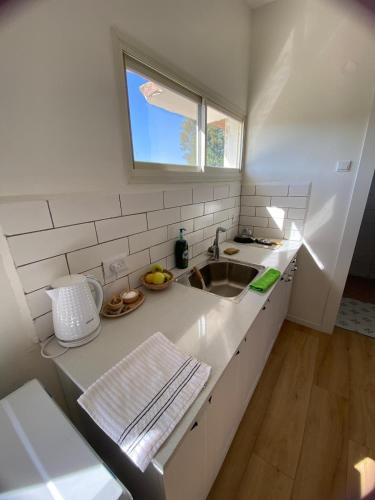 a white kitchen with a sink and a window at Rivers view in kibbutz Dafna in Dafna