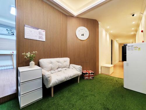 a room with a white chair and a clock on the wall at 부천역 감성 숙소 in Samgong