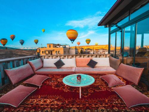 a couch on a balcony with hot air balloons at Alpha Stone House in Göreme