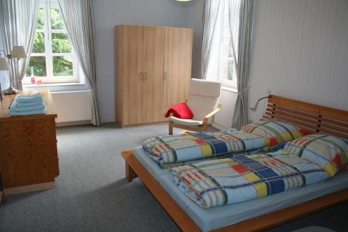 a bedroom with a bed and a chair and windows at Timmermannshof in Xanten