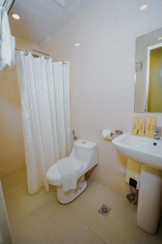 a white bathroom with a toilet and a sink at Olive Town Center and Hotel in Baguio