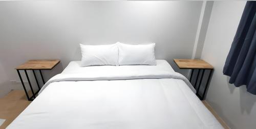 a white bed with two tables in a room at xx GO INN Phuket Old Town in Phuket