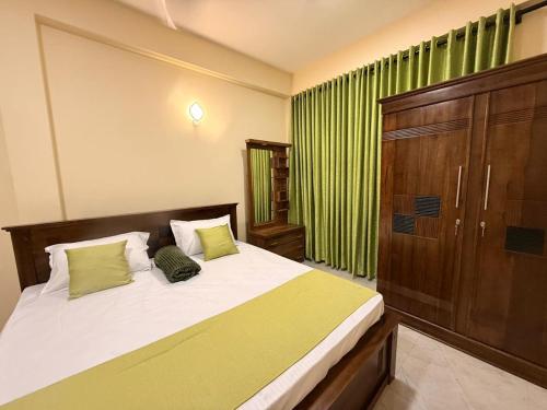 a bedroom with a large bed with green curtains at Wellness Residencies in Colombo