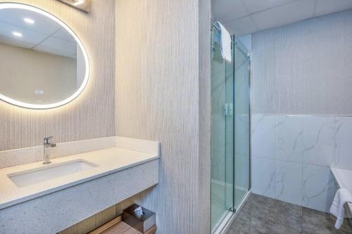 a bathroom with a sink and a glass shower at Quality Suites in Drummondville