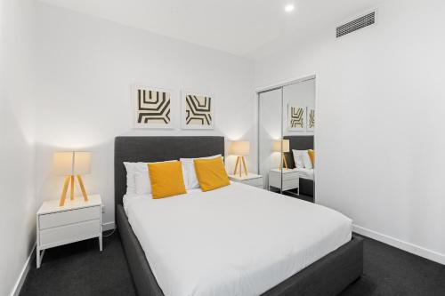 a bedroom with a white bed and yellow pillows at High Street Apartments Toowong in Brisbane