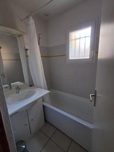 a bathroom with a sink and a tub and a window at Appartement dans résidences de vacances in Salavas