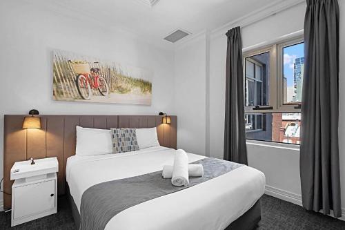 a bedroom with a large white bed with a window at Comfort Apartments Melbourne Central in Melbourne