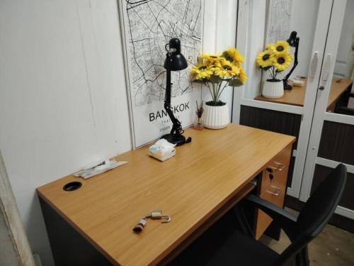 a wooden desk with a lamp and flowers on it at Double Room-C102 in Bangkok