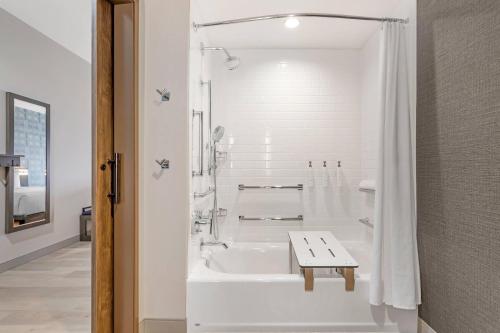 a white bathroom with a tub and a table in it at Cambria Hotel Fort Worth - Medical Center in Fort Worth