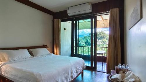 a bedroom with a bed and a view of a balcony at Sang Poy Cottage in Ban Kung Mai Sak