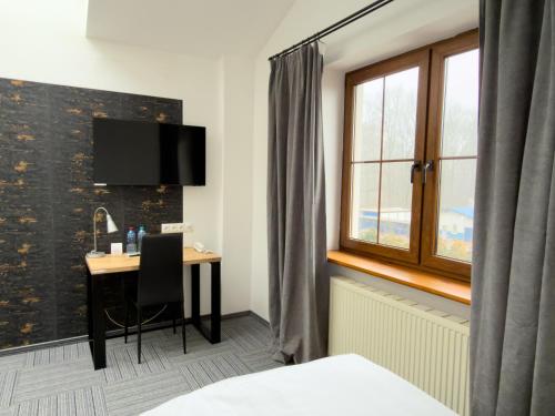 a hotel room with a desk and a window at Hotel Sjesta in Mikołów