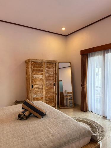 a bedroom with a bed with a dresser and a mirror at Willy Homestay in Uluwatu