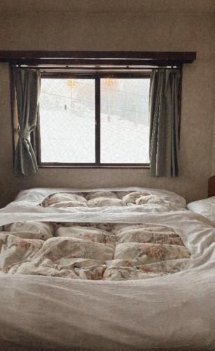 an unmade bed in a bedroom with a window at Yuzawa Hotel New Fukudaya-ski in ski out in Minami Uonuma