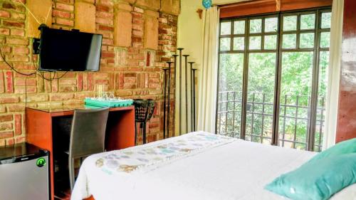 a bedroom with a bed and a tv on a brick wall at Hotel Coyoacan in Mexico City