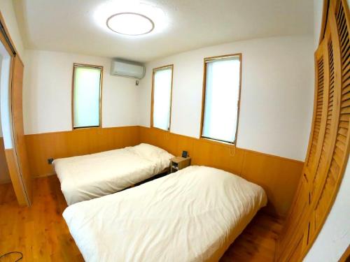 two beds in a small room with windows at CARA-YA(かーらやー） in Ishigaki Island