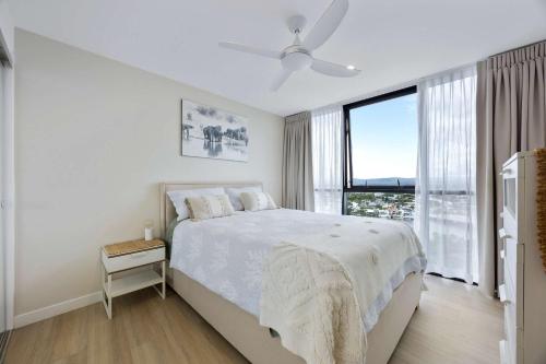 a white bedroom with a bed and a large window at Stylish Beachside Retreat in Gold Coast