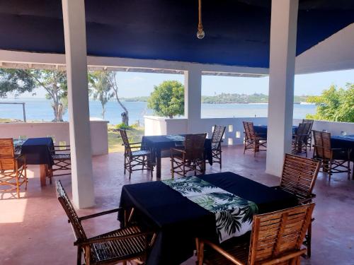 a dining room with tables and chairs and a view of the ocean at Newdarling beach hotel in Watamu