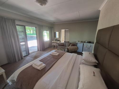 a bedroom with a large bed with two towels on it at Drinkwater Guest Farm in Grootgewaagd