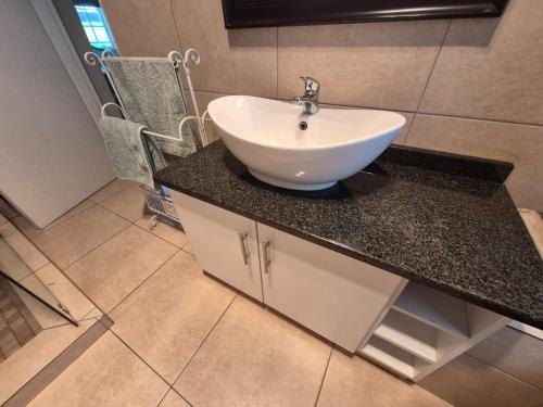 a bathroom with a white sink on a counter at Drinkwater Guest Farm in Grootgewaagd