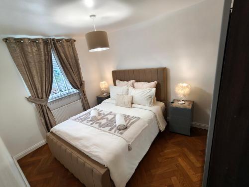 a bedroom with a bed with white sheets and a window at Lovely 2 Bedroom Modern Ground Floor Flat in Clydebank