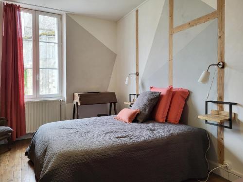 a bedroom with a bed with pink pillows on it at Une nuit à la Clouère in Saint-Maurice-la-Clouère