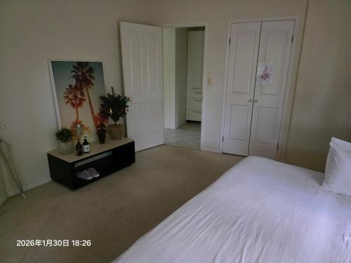 a bedroom with a large white bed and two doors at Gaven Garden in Gold Coast