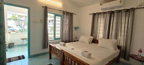 a bedroom with a bed with white sheets and windows at Yog Inn in Varkala