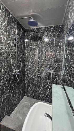 a bathroom with a white sink and a black marble wall at JONIKA Sleep & Go Inn in Aktepa-Chigatay