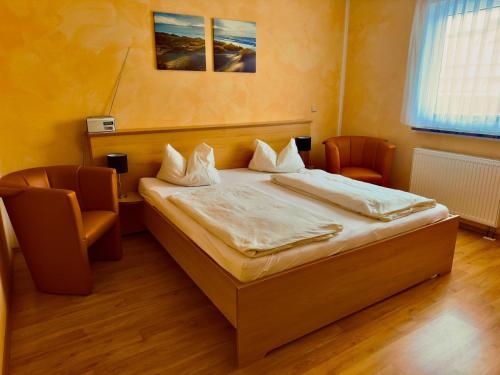 a bedroom with a bed and two chairs in it at Ferienzimmer direkt am See in Priepert