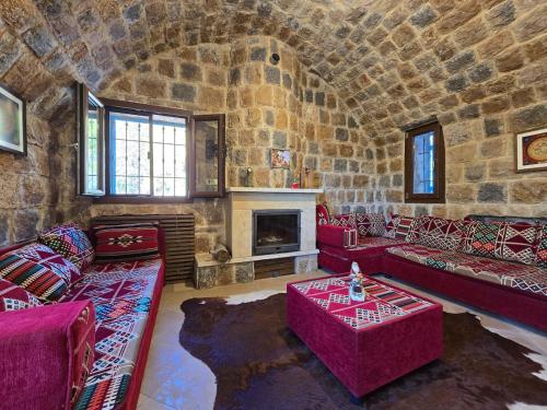a living room with red furniture and a stone wall at FARAYA à10 minutes in Ḩayy al Kanīsah