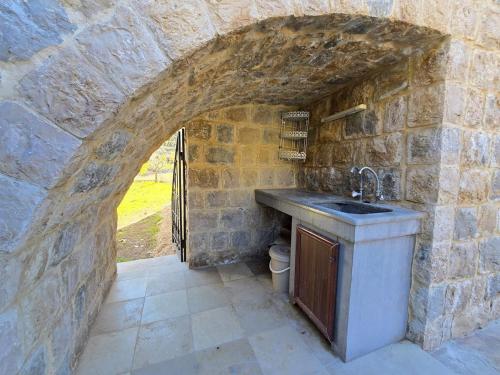 a stone kitchen with a sink in a stone wall at FARAYA à10 minutes in Ḩayy al Kanīsah